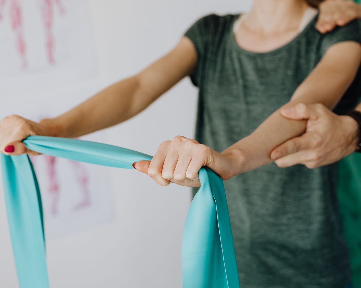A practitioner guiding a person through a resistance band exercise, supporting their arm