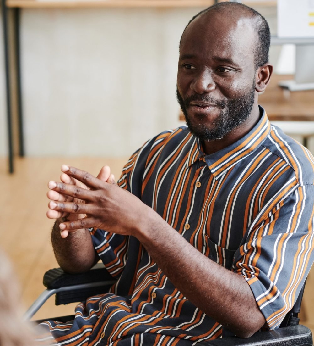 mental-health-support-2048×2048 African disabled businessman sitting in wheelchair and talking to his colleagues at office